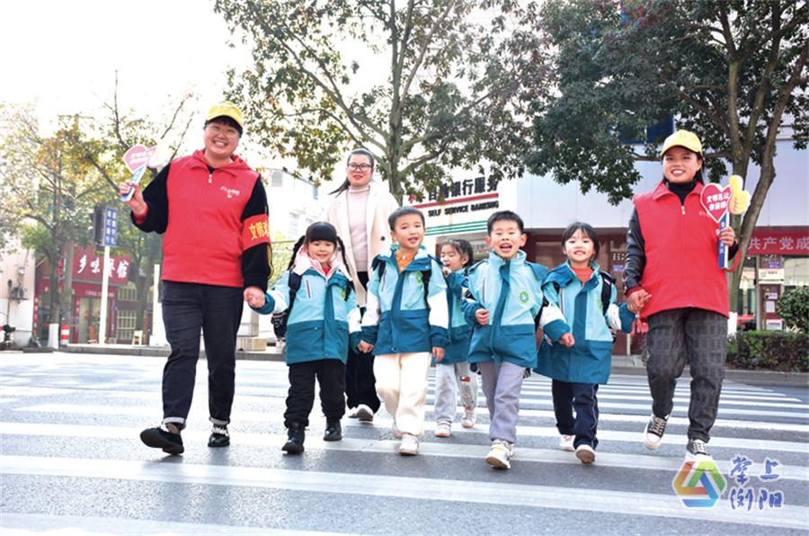 金沙北路和礼花路一段的交叉路口，黄帽子雷锋志愿者引导学生过马路。集里桥社区供图